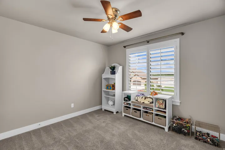 Neutral paint palette with ceiling fan light fixture, carpet flooring, and window with plantation shutters