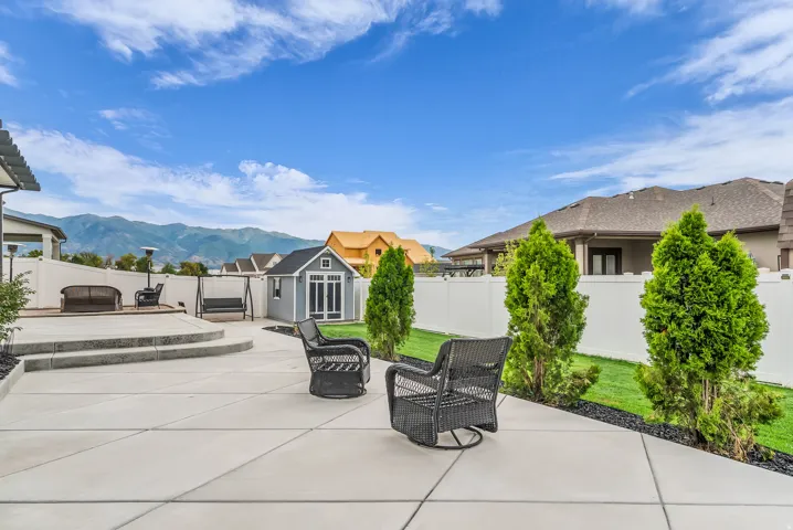 Concrete patio with integrated steps, fenced yard, manicured lawn, and a backyard shed