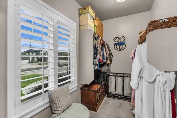Walk-in closet featuring white plantation shutters and light gray wall paint
