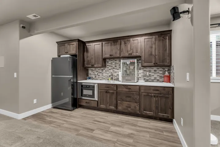 Built-in cabinetry with dark wood finish, white countertop, tile backsplash, and integrated stainless steel appliances