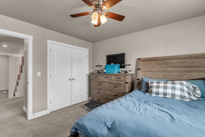 Ceiling fan with integrated lighting, neutral wall paint, carpeted flooring, and white bi-fold closet doors