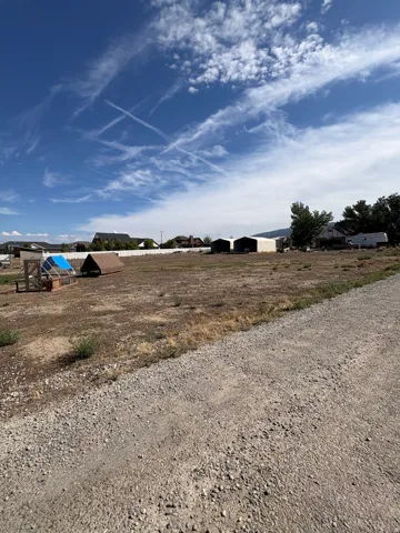 Expansive open lot with distant residential structures and mountain backdrop
