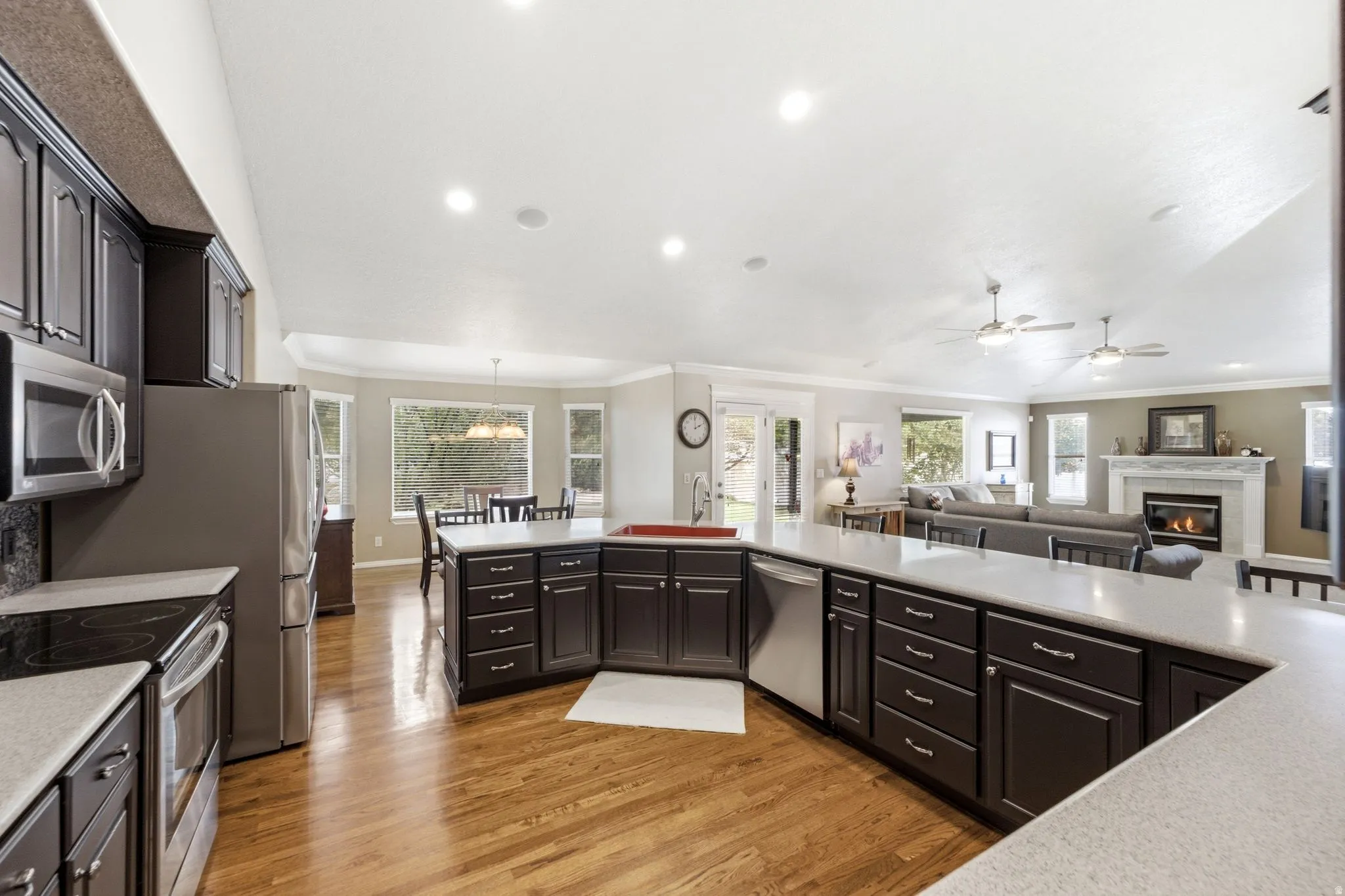Kitchen with dark wood cabinetry, light-toned countertops, stainless steel appliances, and wood-finish flooring