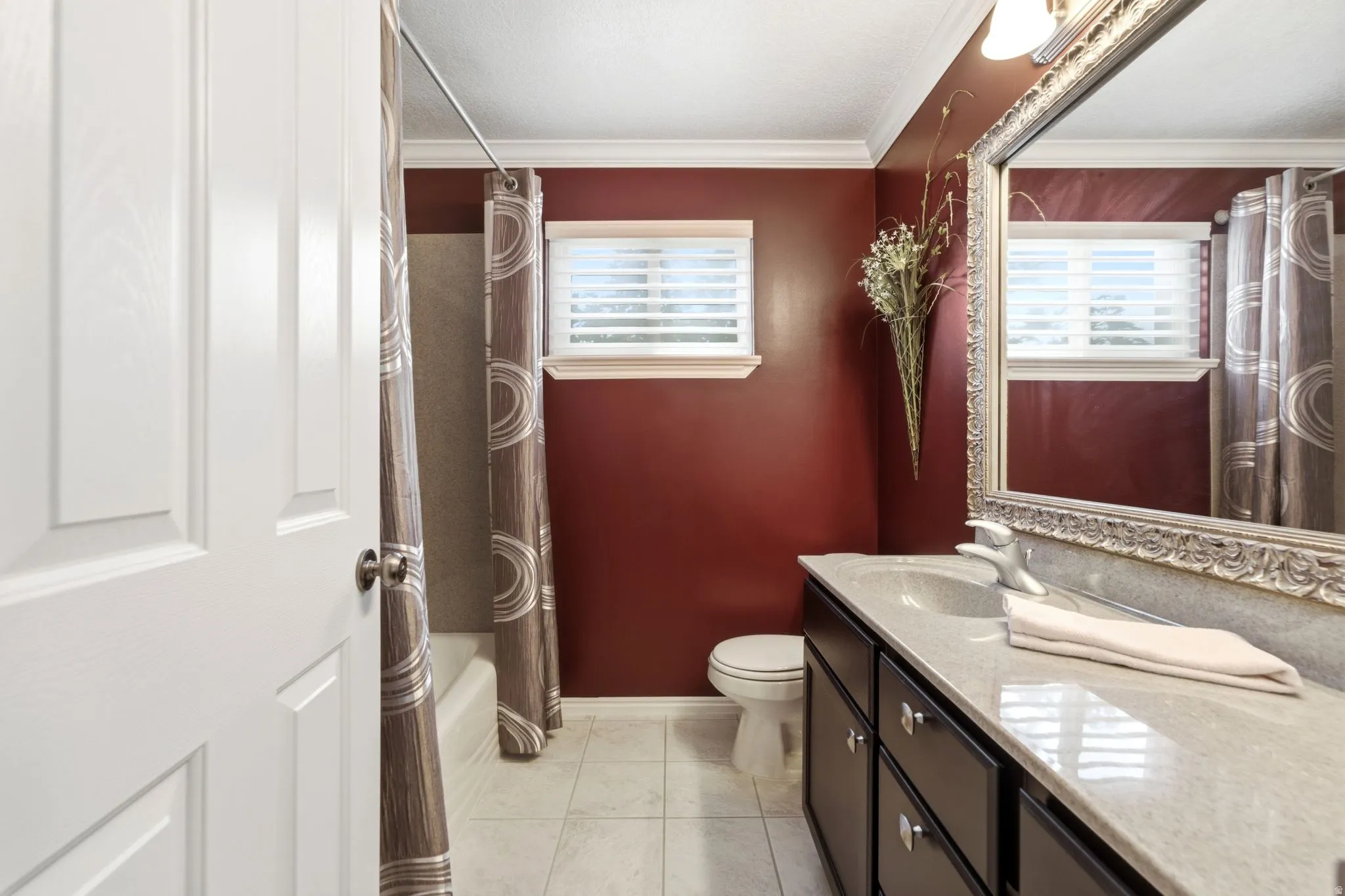 Full bathroom featuring a single vanity with an integrated sink, a framed mirror, and a window with blinds