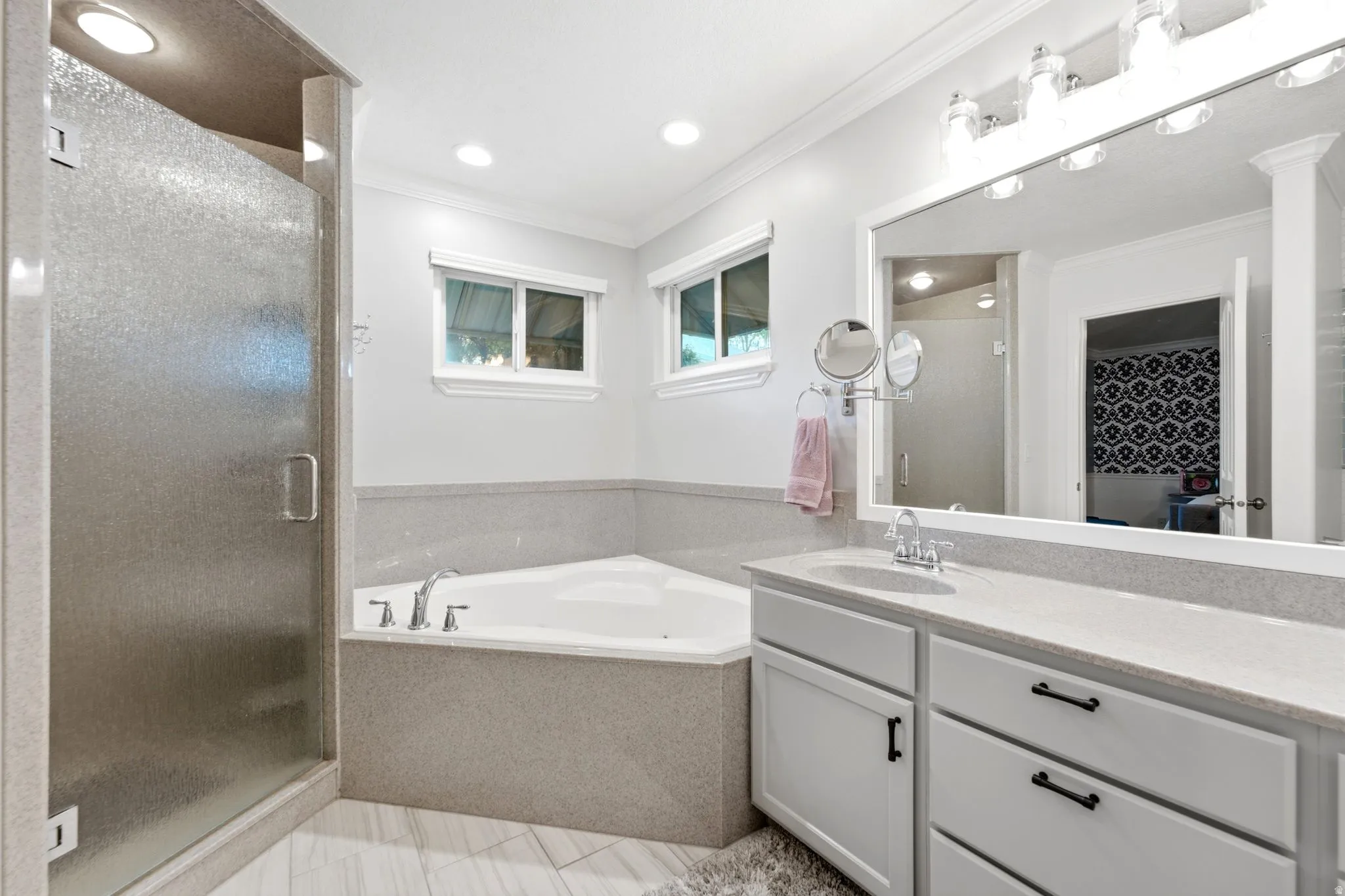 Frosted glass shower enclosure, corner soaking tub, dual windows, single vanity with light-toned countertop, and recessed lighting