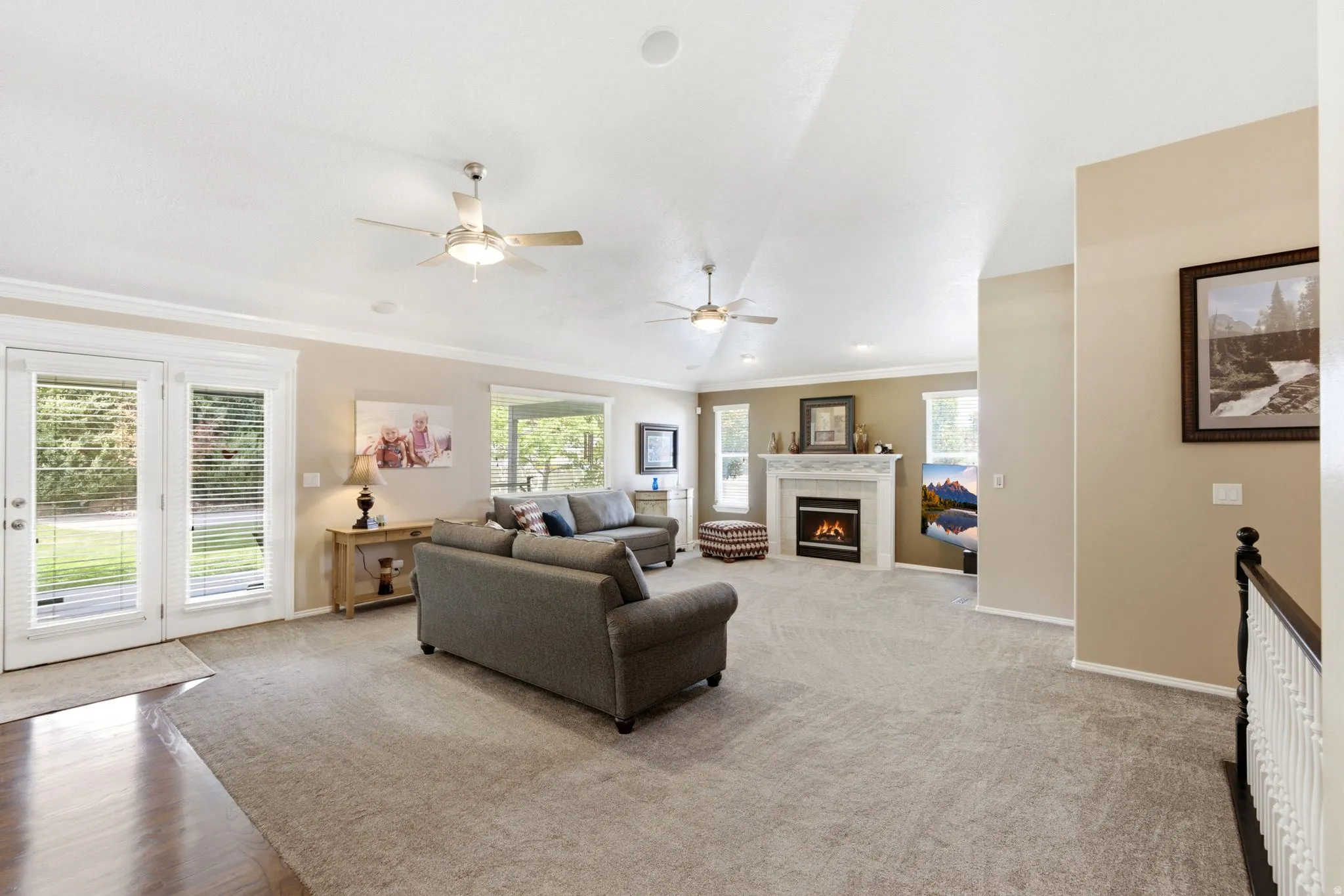 Spacious living area featuring carpet flooring, a fireplace with a mantel, multiple windows, and a set of French doors
