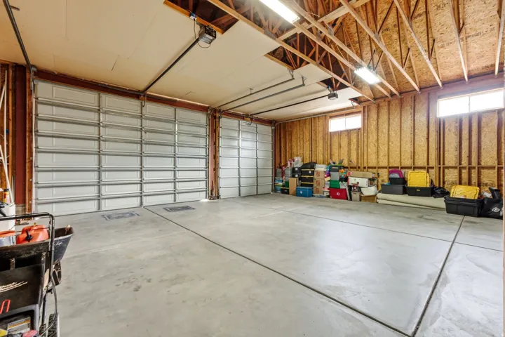 Two overhead garage doors, concrete flooring, exposed wood beam ceiling, and two transom windows