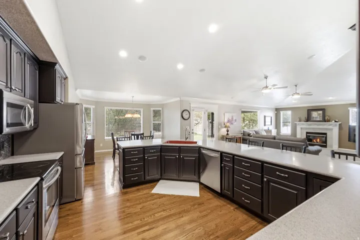 Kitchen with dark wood cabinetry, light-toned countertops, stainless steel appliances, and wood-finish flooring