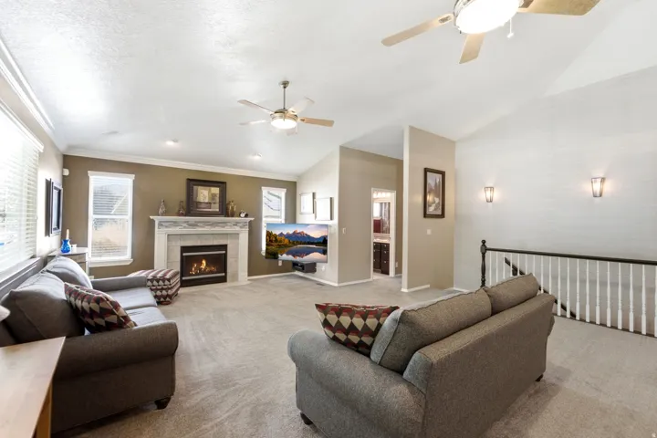 Spacious living area featuring vaulted ceilings, a fireplace with a tiled surround, recessed lighting, and dual ceiling fans