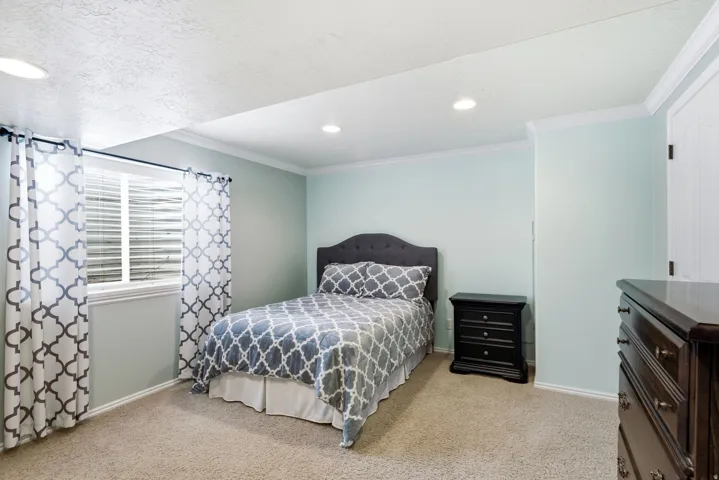 Recessed ceiling lighting, light-toned carpeting, crown molding, a window with horizontal blinds, and a white paneled door