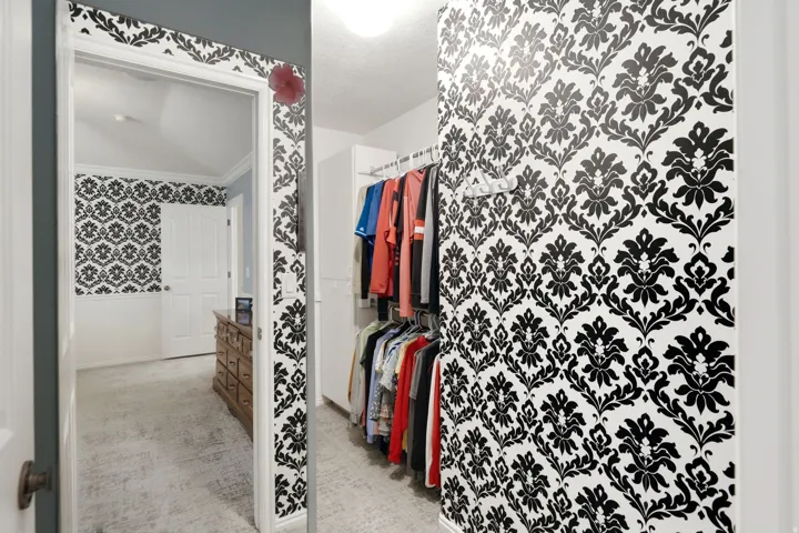 Wall-to-wall carpeting, decorative wallpaper, and built-in closet organization system