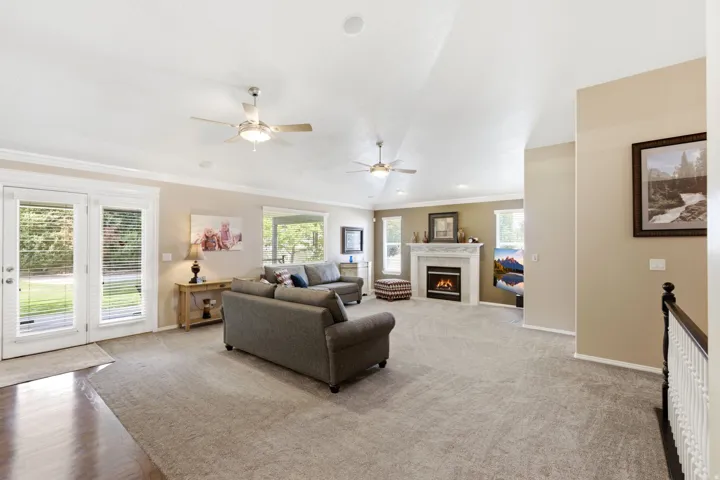 Spacious living area featuring carpet flooring, a fireplace with a mantel, multiple windows, and a set of French doors