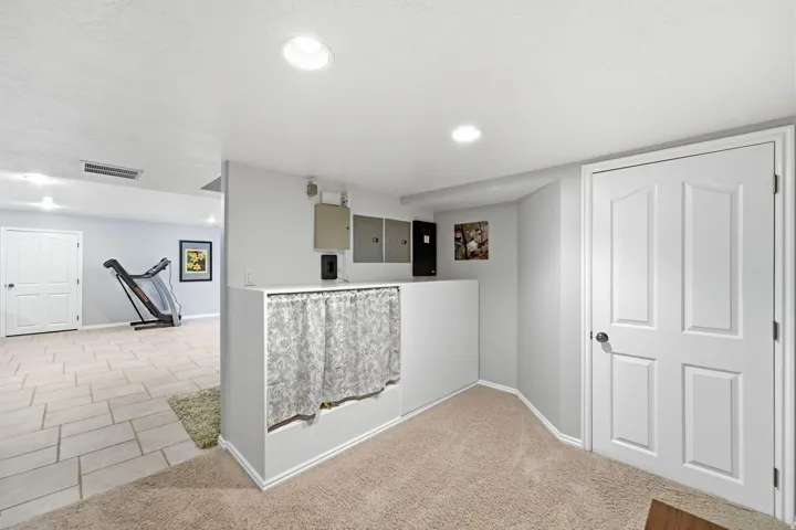 Recessed ceiling lighting, light-toned carpeting, tiled flooring, and a paneled door
