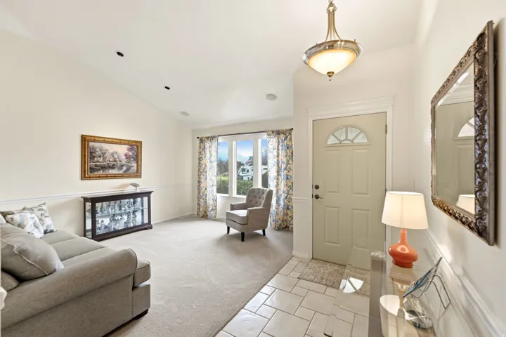 Vaulted ceiling with recessed lighting, wainscoting, bay window, tile entryway flooring, and a decorative front entry door with transom