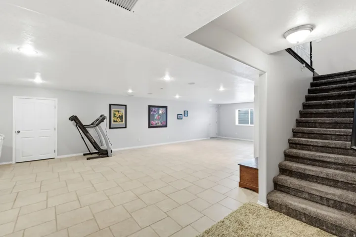 Recessed ceiling lighting, tiled flooring, built-in window, and a carpeted staircase with a metal railing
