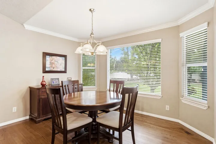Dining area with wood-finish flooring, a tiered chandelier, and multiple windows