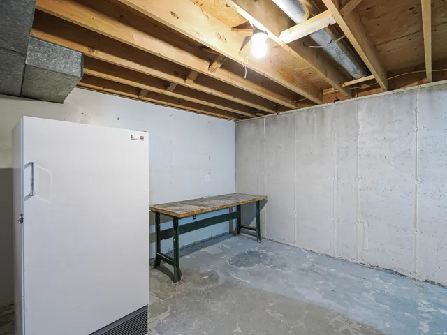 Unfinished basement with exposed ceiling joists, concrete walls, and a concrete floor
