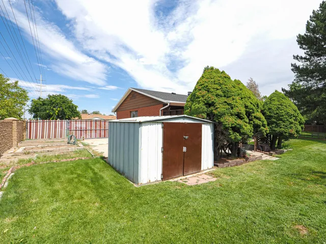 Expansive lawn with mature trees and a detached storage shed