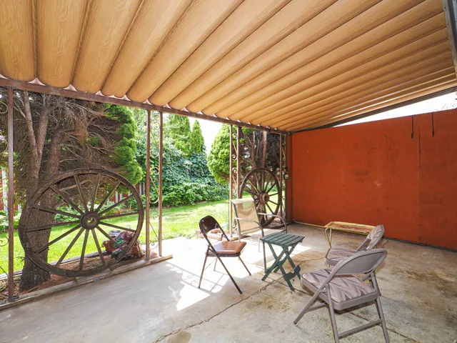 Covered patio with a concrete slab, metal framework, and a solid privacy wall