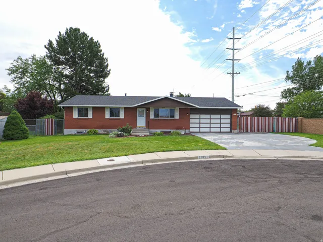 Brick exterior with white window shutters, attached garage with panel door, concrete driveway, and a manicured lawn