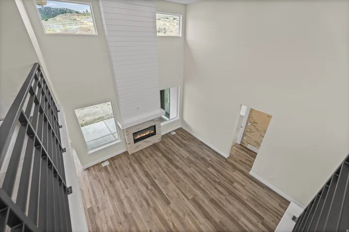 Two-story living area with wood-finish flooring and a contemporary fireplace featuring a shiplap surround and stone tile hearth