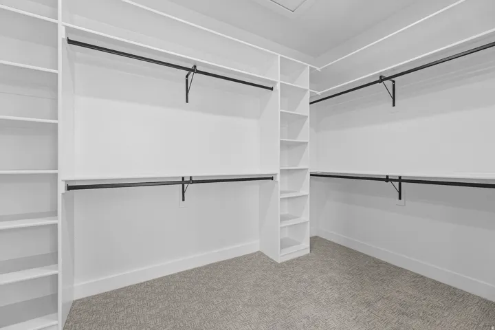 Walk-in closet featuring built-in shelving, multiple hanging rods, and carpet flooring