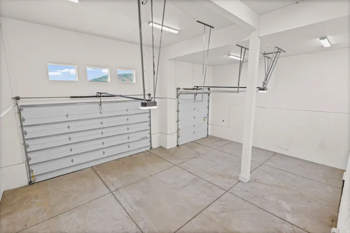 Concrete flooring, two automatic garage doors, upper windows, recessed lighting, and structural support column