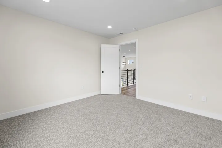 Neutral wall paint with recessed lighting, patterned carpeting, and white trim