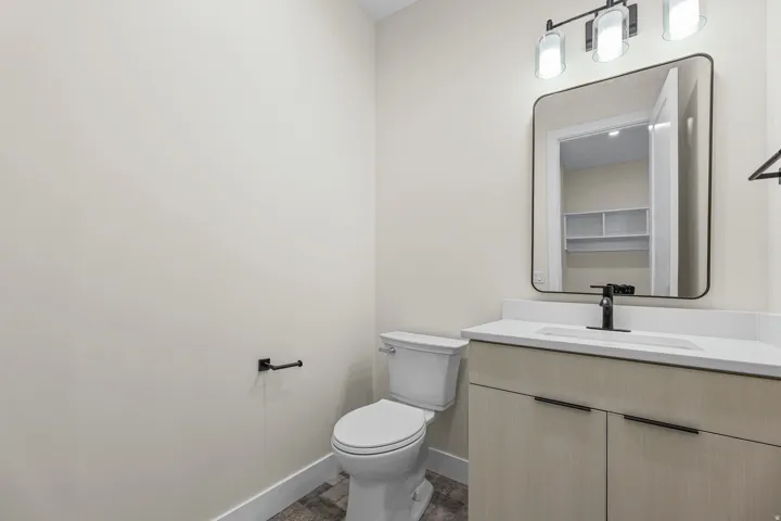 Light wood-finish vanity with black hardware, white countertop, and integrated sink