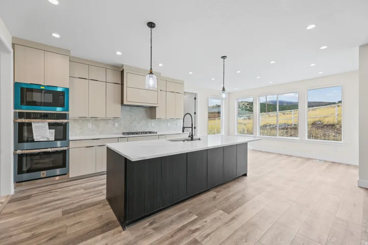 Modern kitchen with light-toned cabinetry, a spacious island featuring a white countertop, and wood-finish flooring