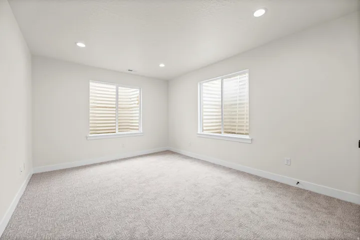 Recessed lighting, light-toned walls, and neutral-toned carpet flooring