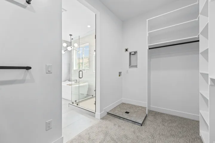 Dedicated laundry area with hookups, built-in shelving, and a walk-in closet featuring a hanging rod