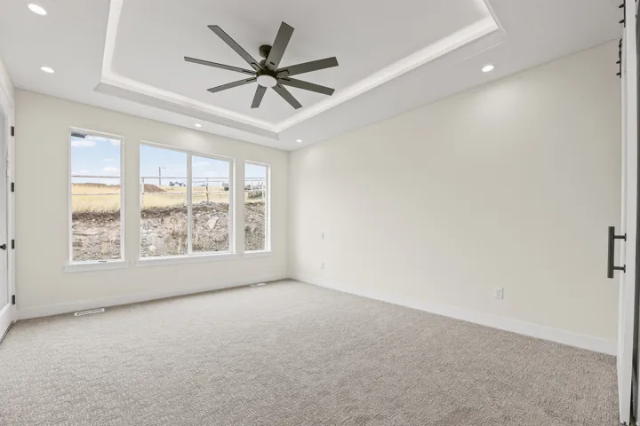 Recessed lighting, tray ceiling, ceiling fan, and light-toned carpet flooring