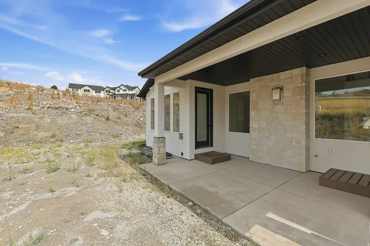 Covered patio featuring a concrete surface, stucco exterior, and stone accent wall
