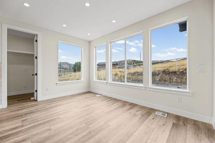 Light-toned wood-finish flooring, recessed ceiling lighting, and multiple windows with white trim