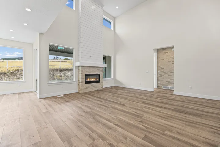 Vaulted ceilings, wood-finish flooring, and an integrated fireplace with a tiled surround