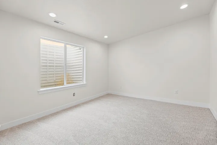 Recessed ceiling lighting, light-colored carpeting, white baseboards, and a white-framed window