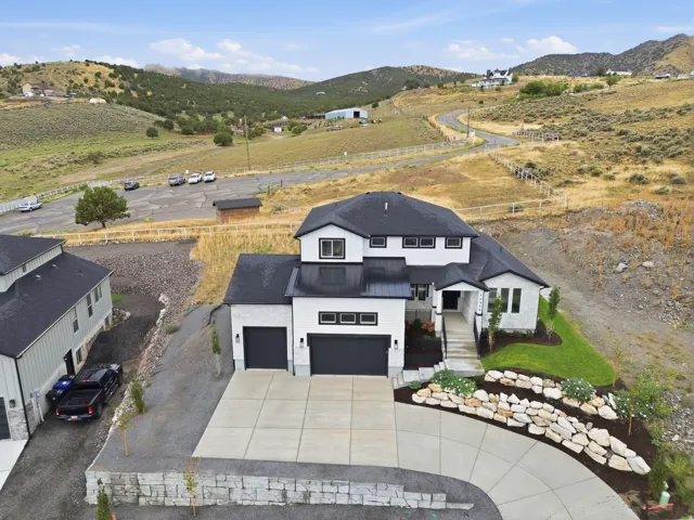 Modern exterior featuring a two-car garage, concrete driveway, and tiered stone landscaping