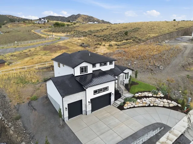 Contemporary residence featuring a black asphalt shingle roof, white exterior siding, black garage doors, and a concrete driveway