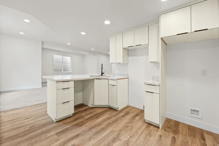 Modern kitchen island with a white countertop and integrated sink, complemented by wood-finish flooring
