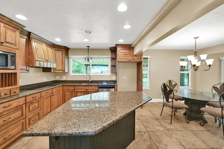 Kitchen featuring wood cabinetry, integrated microwave, granite countertops, and a central island with beadboard detailing