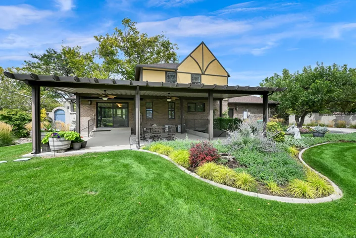Expansive lawn area with a manicured edge, a pergola-covered patio, and a dedicated garden bed