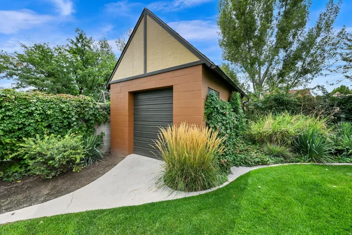 Detached garage with a roll-up door, featuring an A-frame roof and stucco detailing