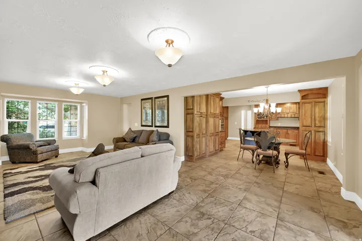 Recessed ceiling lighting, bay window, large format floor tiling, wood cabinetry, and a built-in kitchen hutch