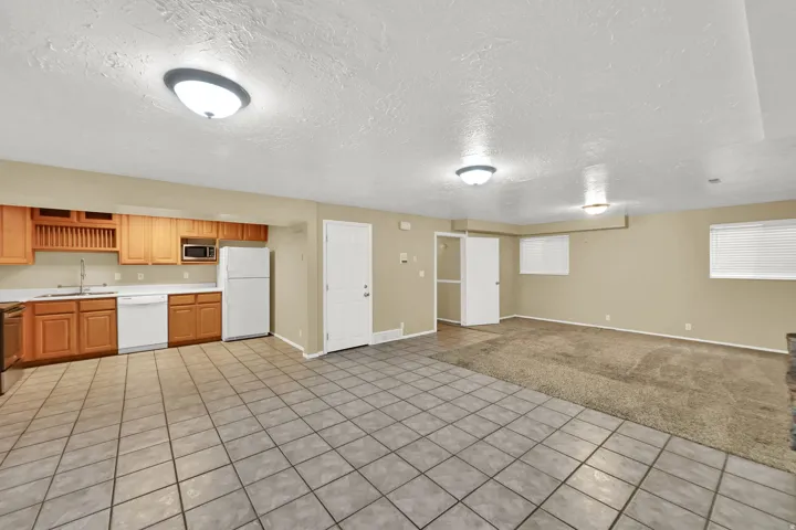Kitchen area with wood cabinetry, white appliances, and a stainless steel sink