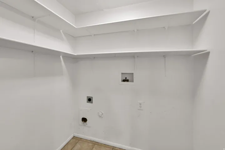 Utility area featuring built-in shelving, tile flooring, and appliance hookups