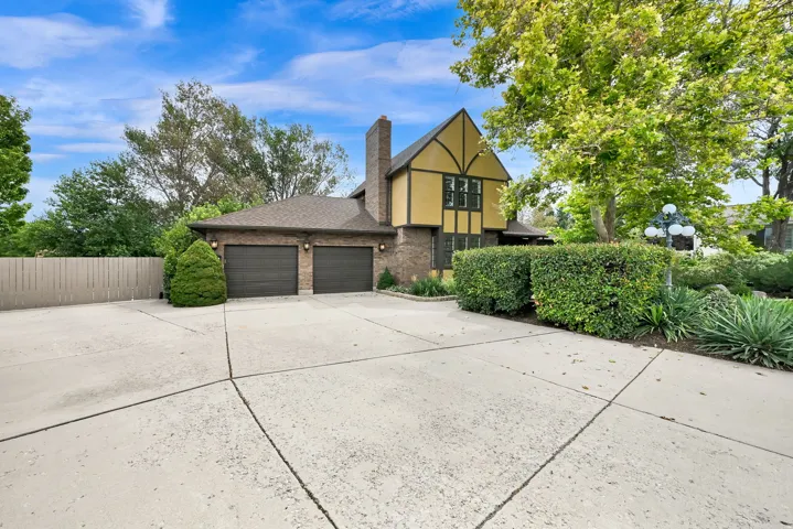 Tudor-style residence with a two-car garage, brick facade, and a concrete driveway