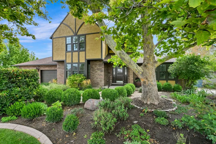Tudor-style exterior with stucco and brick accents, multi-pane windows, and an integrated garage
