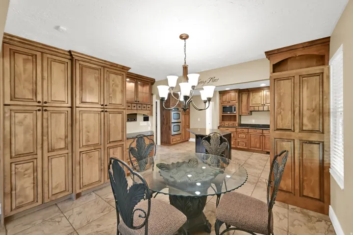 Extensive wood cabinetry, central lighting fixture, tiled flooring, built-in double oven, and integrated microwave