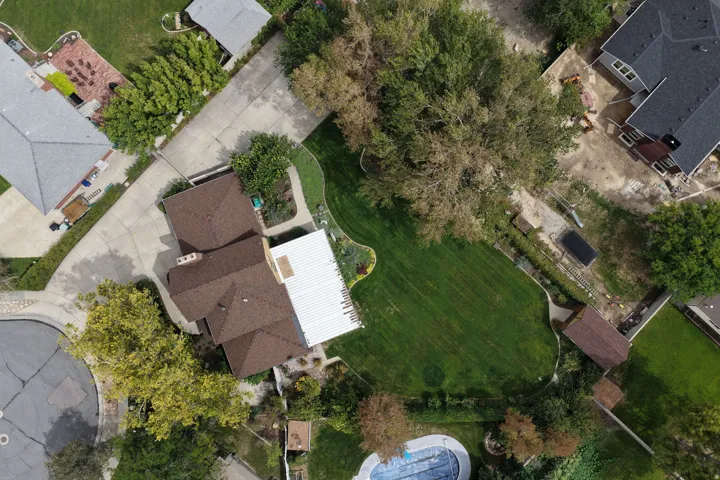 Expansive property featuring a large manicured lawn, established landscaping, and a covered outdoor structure